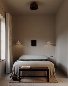 a bed sitting next to a window in a bedroom on top of a hard wood floor