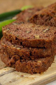 three slices of chocolate zucchini bread sitting on a cutting board next to cucumbers