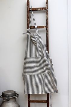 an apron hanging on a ladder next to a potted plant