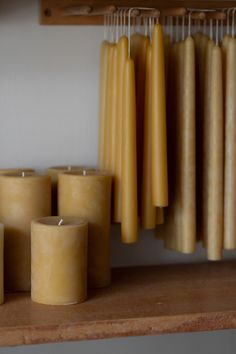 candles are lined up on a shelf in front of some hangers and other items