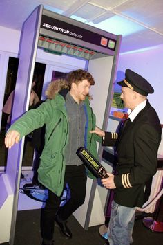 two men are talking to each other in front of a ticket booth at an airport