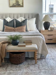 a bed with pillows and blankets on top of it in a bedroom next to a window