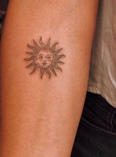 a small sun tattoo on the arm