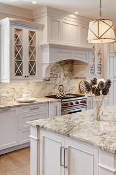 a kitchen with white cabinets and marble counter tops