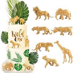 there is a cake decorated with animals and palm leaves on the top, along with other figurines