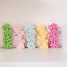 four different colored hair clips sitting on top of a white shelf next to each other