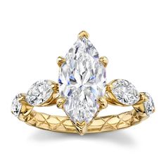 a yellow gold engagement ring with an oval cut diamond and pear shaped diamonds on the band