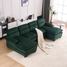 a green sectional couch sitting on top of a wooden floor next to a white rug