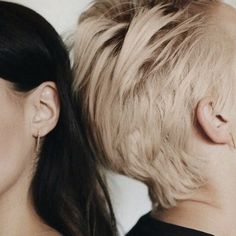 two women with very long hair are facing each other and one has her head shaved