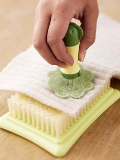 a person using a brush to clean a duster on a wooden table with white towels