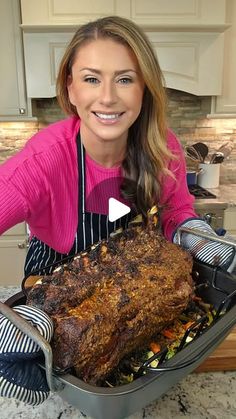 a woman holding a roasting pan full of meat