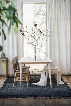 a dining room table with chairs and a vase filled with flowers