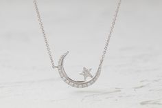 This bright crescent moon features a shining star sitting on its edge. The pave round set diamond adds a gleaming touch. The length is also adjustable, which makes it perfect for layering. White Gold Diamond Necklace With Moon Charm, Celestial Style White Gold Diamond Necklace, Celestial White Gold Diamond Necklace, Round Diamond Necklace With Moon Charm, Celestial Style Round Diamond Necklace In White Gold, Silver Celestial Diamond Necklace, Celestial Silver Round Diamond Necklace, Silver Celestial Round Diamond Necklace, Silver Round Celestial Diamond Necklace