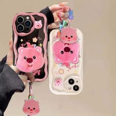 a person holding two cell phones with pink bears on them