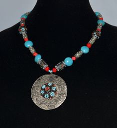 "This hand crafted Afghan necklace has an exotic, tribal look about it. It features a large 2 1/4 inch diameter nickel silver medallion that is garnished with small bead clusters. The design is a well planned cacophony of various bead shapes, sizes and colors. The necklace itself measures 14 inches in length. It is in excellent vintage condition. The necklace is a runway style show stopper! We ship to most International Locations. Our \"Everywhere Else\" shipping that gets added to an internatio Blue Medallion Necklace For Festivals, Blue Medallion Necklace For Festival, Bohemian Round Beaded Necklaces Nickel Free, Bohemian Style Round Medallion Necklace For Festival, Bohemian Round Medallion Necklace For Festival, Bohemian Beaded Necklaces With Silver Beads, Bohemian Silver Beaded Necklace With Round Pendant, Nickel Free Red Necklace For Festival, Traditional Handmade Round Medallion Necklace