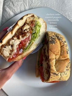 a hand holding a sandwich on a plate with the words chicken, peppers, lettuce and tomato