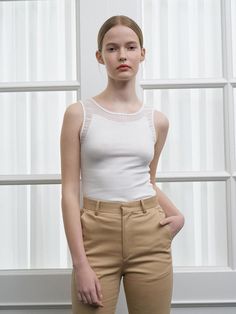 The Selena Sleeveless Top is a testament to timeless style with its classic tank silhouette and delicate neckline detailing. Tailored to skim the body, this top offers a balance of comfort and poise, making it a staple for any wardrobe. Its understated elegance is amplified by the soft, ribbed detailing along the trim, adding a hint of femininity to the piece. - The Selena Sleeveless Top features a ribbed neckline and armholes for a refined, textural touch.- Crafted to contour gracefully to the body, it ensures a flattering fit for a range of body types.- Its sleeveless design makes it a versatile layering option under blazers or cardigans, as well as a stand-alone piece in warmer weather.- The top's simplistic nature allows for endless styling possibilities, pairing seamlessly with b White Sleeveless Tank Top With Minimal Stretch, Elegant Stretch Fine Knit Tank Top, Fitted Fine Knit Elegant Tank Top, Elegant Fitted Fine Knit Tank Top, Elegant Fine Knit Fitted Tank Top, Classic Scoop Neck Tank Top For Spring, White Sleeveless Tank Top, Elegant Fitted Tank Top With Scoop Neck, Fitted Seamless Tank Top For Spring