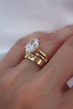 a woman's hand with two gold rings and a diamond ring on her finger