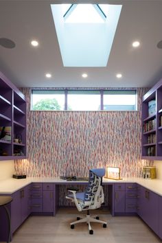 an office space with purple cabinets and white desks, along with a skylight