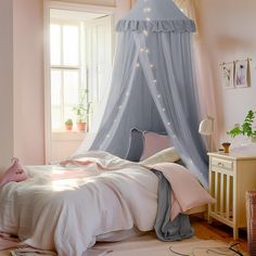 a bedroom with pink walls, white bedding and a blue canopy over the bed