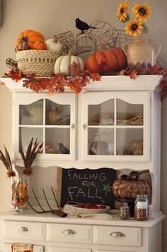 a white hutch filled with lots of fall decorations