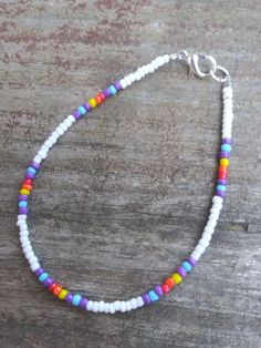 a white beaded bracelet with multicolored beads on a wooden surface, close up