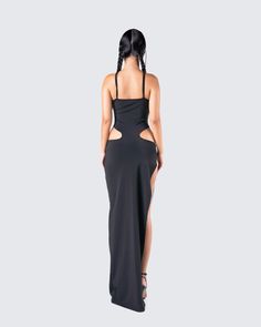 the back of a woman wearing a black dress with cut out sides and high slits