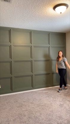 a woman standing in an empty room with green garage doors on the wall and carpet