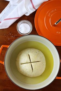 an orange pot with some bread in it and other items on the table next to it