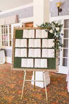 a table with many books on it and flowers in front of the menu board that has been set up