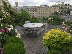 a table and chairs on a wooden deck surrounded by flowers