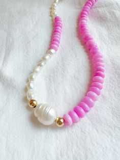 a pink and white beaded necklace on a white shirt with gold accents, beads and pearls