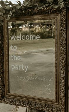 a mirror that is on the side of a building with a welcome to the party sign in it