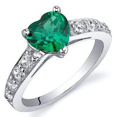 a green heart shaped ring with diamonds on the sides and an accent band around it