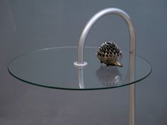 a glass table with a metal handle and a small hedgehog on it's side