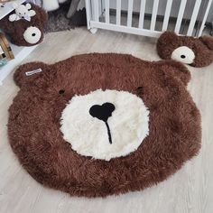 a brown teddy bear rug sitting on top of a floor next to a crib