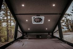 the inside of a camper with its door open and lights on in front of trees