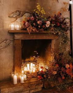 a fireplace with candles and flowers on it