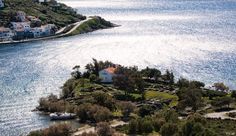 an island in the middle of some water with houses on it and boats parked near by