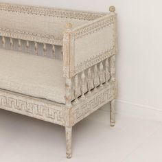 an antique white crib sitting against a wall