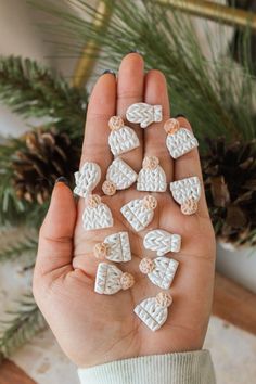 a person is holding some tiny white objects in their hand with pine cones on the background