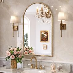 a bathroom with a sink, mirror and flowers on the counter