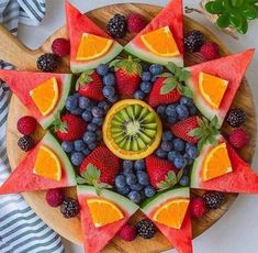 a wooden plate topped with sliced fruit and watermelon