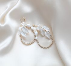 Introducing our stunning CELENA hoop earrings, perfect for weddings or any special occasion. Handcrafted with delicate white opal crystals and elegant freshwater pearls and flowers, these earrings add a touch of glamor and sophistication to any outfit. Make a statement with our gold floral hoops! - Handcrafted in my PA studio with genuine white opal Austrian crystals- Freshwater pearls- Polymer clay flowers and leaves- Yellow gold finish is pictured. Available in rose gold, yellow gold or rhodium (silver)- Earrings measure 2.5 inches x 1.5 inch- Handcrafted in the US.- Nickel free and hypoallergenic- PLEASE ALLOW APPROX 10 BUSINESS DAYS FOR COMPLETION BEFORE SHIPPING.This is an original design by © Treasures by Agnes Gold Wedding Earrings With Handmade Flowers, Elegant Gold Bridal Earrings With Handmade Flowers, Whimsical Gold Flower Earrings For Wedding, Elegant White Floral Earrings, Clay Wedding Earrings Floral, Bridal Backdrop Necklace, Bridal Statement Earrings, Backdrops Necklace, Statement Hoop Earrings