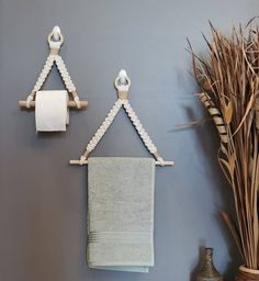 two towels are hanging on the wall next to a vase with dried grass in it