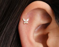 a close up of a person's ear with a butterfly piercing