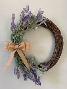 a lavender wreath with a bow hanging on the wall