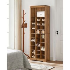 a wooden shoe rack filled with shoes next to a white bed in a living room