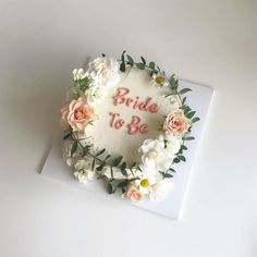 a wedding cake with flowers and the bride to be written on it