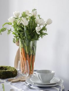 a vase filled with white flowers sitting on top of a table next to a plate